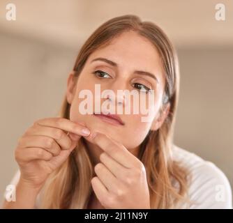 Ich bin mir sicher, dass das verschwinden wird, wenn ich es auslasse Kurzer Schuss einer jungen Frau, die einen Pickel auf ihr Gesicht quetscht. Stockfoto