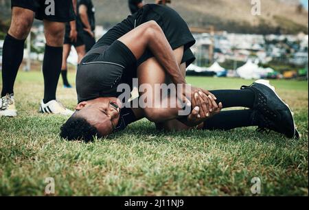 Rugby ist ein Sport, der mit vielen Verletzungen kommt. Kurzer Schuss eines hübschen jungen Rugby-Spielers, der auf dem Spielfeld verletzt wurde. Stockfoto