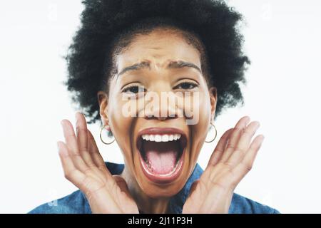 OMM. Studioaufnahme einer attraktiven jungen Frau, die überrascht aussaunt und mit offenem Mund vor grauem Hintergrund posiert. Stockfoto