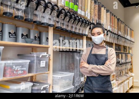 Porträt einer afroamerikanischen Besitzerin eines nachhaltigen kleinen lokalen Unternehmens in einer umweltfreundlichen Baumwollmaske Stockfoto