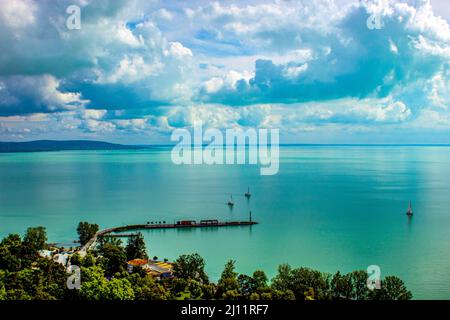 Der Plattensee von Tihany im Sommer. Das klare Wasser mit einem kleinen Hafen und den Wolken. Stockfoto