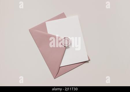 Leere Hochzeitskarte, Einladungsmockup-Szene im Sonnenlicht. Nahaufnahme eines pinken Umschlags mit dekorativem Wachsverschluss auf dem Tisch. Geburtstagsbriefpapier Stockfoto