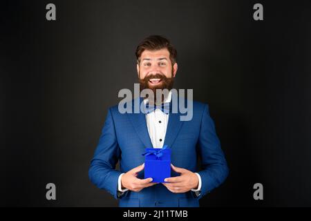 Stauned glücklich Mann in Smoking Fliege mit Geschäft Belohnung Box. Anlass Gruß. Stockfoto