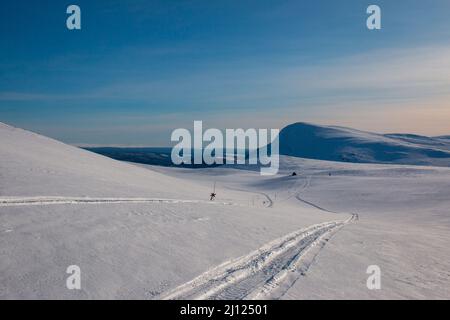 Ein Winter-Ski- und Schneemobil-Trail bergab in Richtung Notunterkunft. Kungsleden Trail zwischen Hemavan und Ammarnas, Lappland, Schweden, Anfang März. Stockfoto