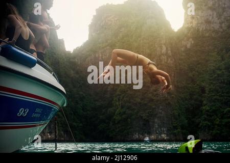 Leben Sie ohne Reue. Aufnahme einer jungen Frau, die einen Rückschlag von einem Boot macht, während ihre Freunde zusehen. Stockfoto