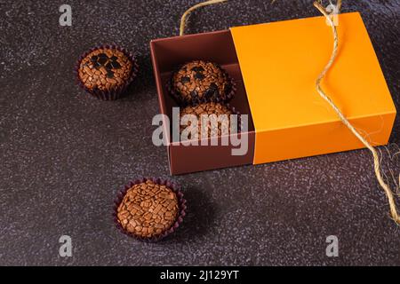 Brigadeiros, traditionell und bitter, außerhalb und innerhalb der Box. Traditionelle brasilianische Süßigkeit. Stockfoto