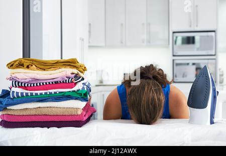 Den Shes geht der Dampf aus. Aufnahme einer jungen Frau mit dem Kopf nach unten auf einem Bügelbrett. Stockfoto