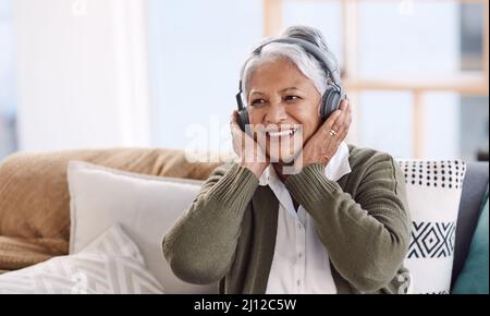 Einige Stücke werden mein Favorit bleiben für immer. Aufnahme einer älteren Frau, die Kopfhörer trägt, während sie zu Hause Musik hört. Stockfoto