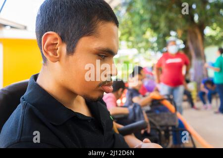 Managua, Nicaragua, März 21. 2022: Ein junger Latein mit psychischen Erkrankungen und Blindheit sitzt still, während Spiele und Aktivitäten stattfinden Stockfoto