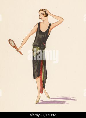 Frau mit bob-Haarschnitt in einem asymmetrischen Abendkleid, das einen Spiegel hält., 1924. Robe du Soir, nach einer Skizze des Designers Worth. 1924. Handkolorierte Chorlithographie von Marcel Bry aus Raymonde Sees Le Costume de la Revolution a nos Jours, Editions de la Gazette des Beaux-Arts, Paris, 1929. Stockfoto