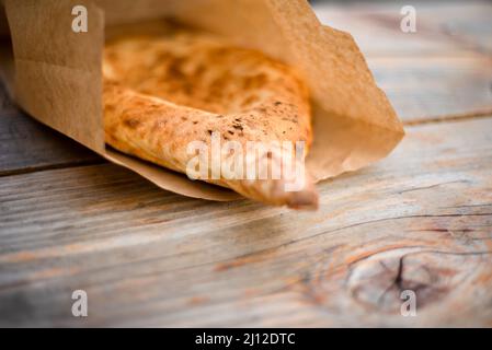 Ethnisches Brot in einer Papiertüte auf einem Holztisch. Pita. Kuchen. Ökologische Lebensmittel. Stockfoto