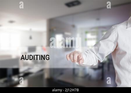 Drücken Sie mit der männlichen Hand auf das Wort Auditing in einer Anzeigefalste der virtuellen Suche. Business Finance-Konzept. Stockfoto