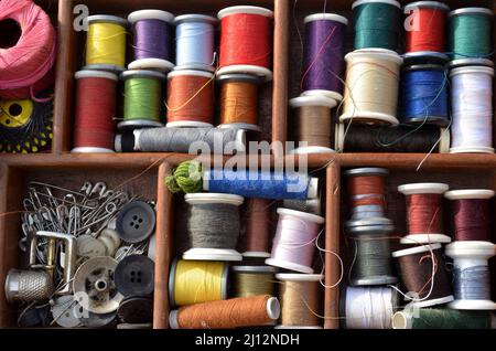 Blick in einen Arbeitskorb mit Spulen Nähgarn in vielen Farben. Stockfoto