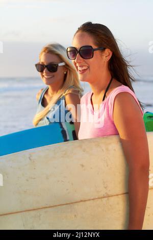 Surfen mit meinem Bestie. Kurzer Shot von zwei attraktiven jungen Surferinnen. Stockfoto