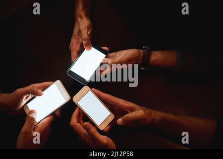 Gemeinsam Pläne wie ein Chef machen. Nahaufnahme einer Gruppe von nicht erkennbaren Personen, die auf ihrem Telefon SMS schreiben, während sie nachts in einer Bar sitzen. Stockfoto