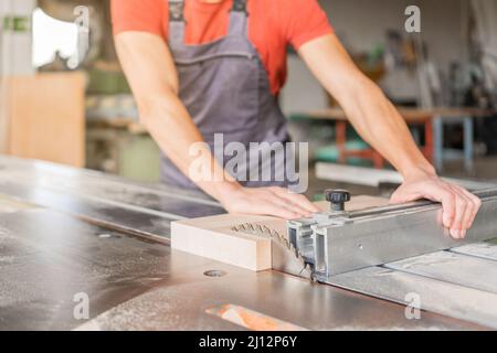 Unerkennbarer Zimmermann, der am Schiebesägetisch arbeitet Stockfoto