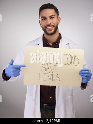 Ich habe es einfach gemacht und tue es. Aufnahme eines hübschen jungen Arztes, der allein im Studio steht und ein Poster hochhält. Stockfoto