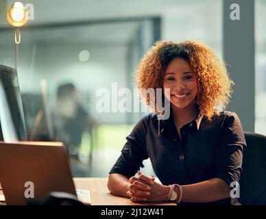 Seid ihr bereit für die Nachtschicht, weil ich es bin. Porträt einer glücklichen jungen Geschäftsfrau, die während eines späten Abends auf der Arbeit einen Laptop benutzt. Stockfoto