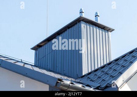 Belüftungssystem mit Schornsteinen und Kanälen auf dem Dach eines Wohngebäudes Stockfoto