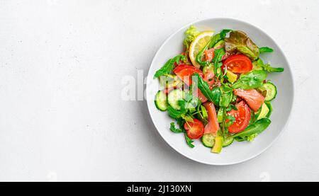 Salat mit Lachs, Gemüse und frischen Kräutern auf hellem Hintergrund. Diätetischer, gesunder Salat. Stockfoto
