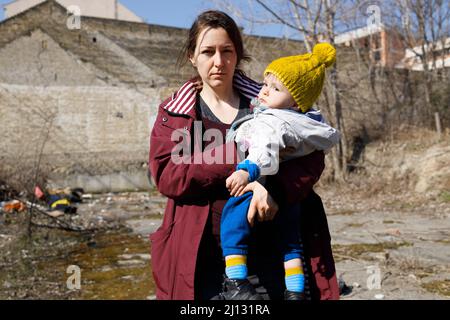 Weibliche Zivilistin hält ihr Kind in den Ruinen Stockfoto