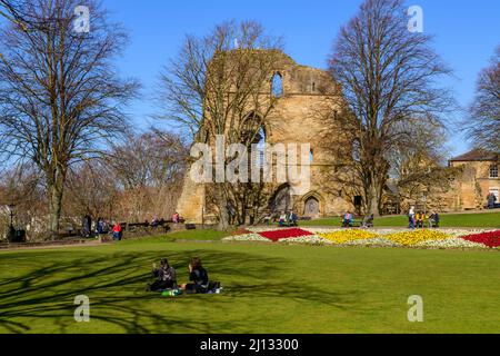 Menschen sitzen entspannt Sonne genießen (helle Border Blumen, alten Turm halten Ruinen, blauer Himmel) - Knaresborough Castle, North Yorkshire, England, Großbritannien. Stockfoto