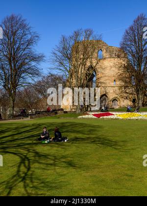 Menschen sitzen entspannt Sonne genießen (helle Border Blumen, alten Turm halten Ruinen, blauer Himmel) - Knaresborough Castle, North Yorkshire, England, Großbritannien. Stockfoto