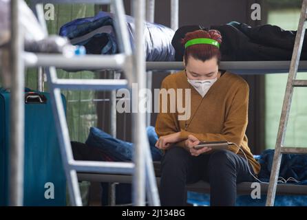 Bad Kreuznach, Deutschland. 21. März 2022. Daria sitzt auf ihrem Lagerbett und liest die Nachrichten von Freunden auf ihrem Handy. Die 19-jährige Ukrainerin ist zusammen mit ihrer Mutter und ihren beiden Schwestern im Notheim in Bad Kreuznach untergebracht. (To dpa-Korr 'Horrormomente sind auch in Bad Kreuznach allgegenwärtig') Quelle: Boris Roessler/dpa/Alamy Live News Stockfoto