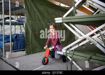 Bad Kreuznach, Deutschland. 21. März 2022. Ein Mädchen aus der Ukraine fährt mit einem gespendeten Roller zwischen den Kinderbetten im Notunterstand. (To dpa-Korr 'Horrormomente sind auch in Bad Kreuznach allgegenwärtig') Quelle: Boris Roessler/dpa/Alamy Live News Stockfoto