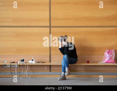 Bad Kreuznach, Deutschland. 21. März 2022. Eine Frau hat sich in eine Ecke im Notunterstand in Bad Kreuznach zurückgezogen, um einen Anruf zu tätigen. Das Gymnasium beherbergt derzeit fast nur Flüchtlingsfrauen und -Kinder. (To dpa-Korr 'Horrormomente sind auch in Bad Kreuznach allgegenwärtig') Quelle: Boris Roessler/dpa/Alamy Live News Stockfoto