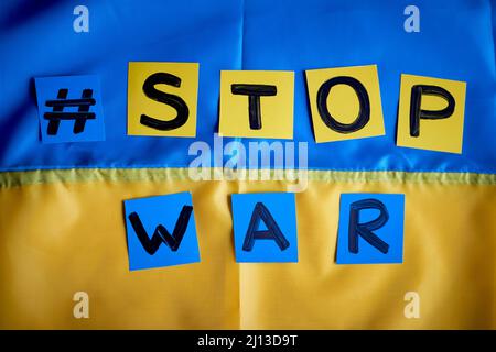 Papier gezeichnetes Banner Stop war Hashtag auf ukrainischer Flagge gelb-blauer Hintergrund. Kinder unterstützen die Ukraine, bleiben bei der Ukraine Stockfoto