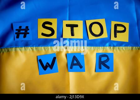 Papier gezeichnetes Banner Stop war Hashtag auf ukrainischer Flagge gelb-blauer Hintergrund. Kinder unterstützen die Ukraine, bleiben bei der Ukraine Stockfoto