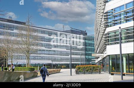 Düsseldorf (Vodafone Campus) – März 9. 2022: Blick über den Platz auf moderne Gebäude gegen blauen Himmel, flauschige Wolken Stockfoto