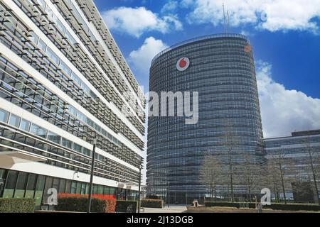 Düsseldorf (Vodafone Campus) – März 9. 2022: Blick über den Platz auf ein futuristisches Gebäude mit Turm gegen blauen Himmel mit flauschigen weißen Wolken Stockfoto