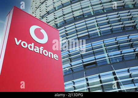 Düsseldorf (Vodafone Campus) – März 9. 2022: Blick auf die rote Säule gegen futuristischen Gebäudeturm und blauen Himmel, flauschige Wolken Stockfoto