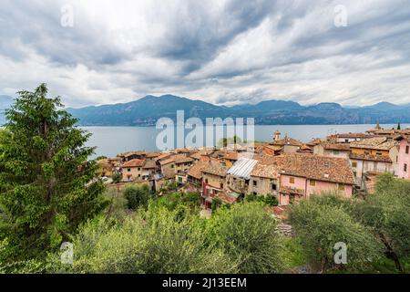 Kleines Dorf Castelletto di Brenzone und Panoramablick auf den Gardasee mit der lombardischen Küste im Hintergrund. Brenzone sul Garda, Venetien, Italien Stockfoto