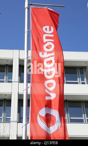 Düsseldorf (Vodafone Campus) – März 9. 2022: Blick auf rote Fahne mit Logo-Schriftzug gegen Gebäude und blauen Himmel Stockfoto