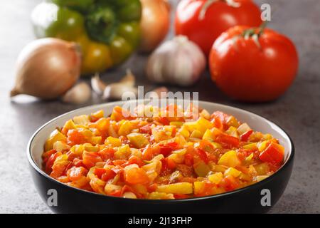 Hausgemachte Soffrito-Sauce aus Paprika, Tomaten, Knoblauch und Zwiebeln in Nahaufnahme in einem Teller auf dem Tisch. Horizontal Stockfoto
