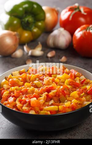 Sofrito ist eine Grundsauce aus grünem Pfeffer, Zwiebeln, Tomaten, Knoblauch und anderen Gewürzen, die in der Schüssel auf dem Tisch in der Nähe stehen. Vertikal Stockfoto