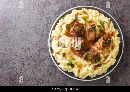 Griechischer Sofrito Traditionelles Rindergericht mit Kartoffelpüree aus Korfu mit Kartoffelpüree in der Nähe auf dem Teller auf dem Tisch. Horizontale Draufsicht von A Stockfoto