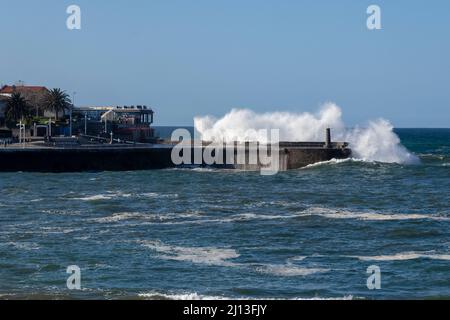 Wellen schlagen an einem sonnigen Tag gegen den Hafen von lekeitio in der kantabrischen See Stockfoto