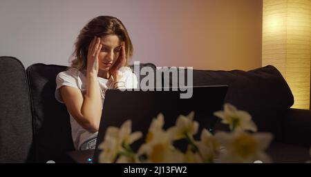 Junge Frau, die allein am Laptop arbeitet, lebt spät in der Nacht im Dunkeln Stockfoto