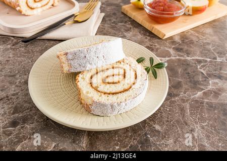 Zwei zarte Apfelrollen in Puderzucker auf einem Teller auf einem Marmortisch. Köstliches Dessert, Snack Stockfoto