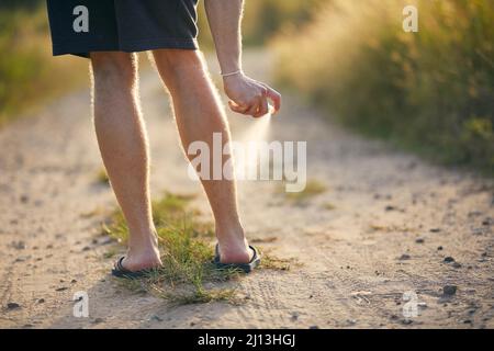 Prävention gegen Mückenstich. Mann, der Insektenschutzmittel auf seine Beine applyte. Stockfoto