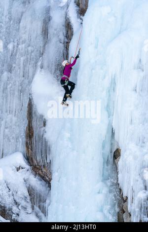 Eine Eiskletterin, die im Ouray Ice Park in Colorado mit Eispickeln und Steigeisen eine Eiswand bestiegen hat. Stockfoto