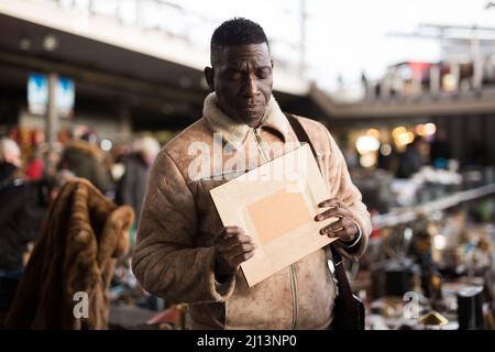 Afroamerikanischer Mann wählt Antiquitäten auf dem Flohmarkt Stockfoto