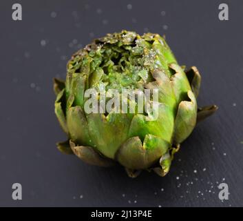 Gekochte Artischocken auf schwarzem Steinbrett Stockfoto