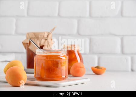 Hausgemachte Aprikosenmarmelade im Glas auf weißem Hintergrund der Küche. Sommerernte und Konserven. Nahaufnahme. Speicherplatz kopieren. Stockfoto