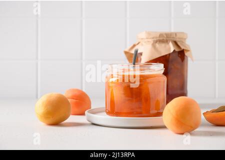 Hausgemachte Aprikosenmarmelade im Glas auf weißem Hintergrund der Küche. Sommerernte und Konserven für den Winter. Leckeres Dessert. Nahaufnahme. Stockfoto