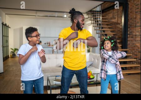 Mann und Kinder bewegen ihre Hände auf die gleiche Weise Stockfoto